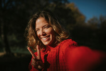 Smiling Woman Wearing Red Sweater And Showing Peace Sign