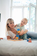 © Westend61 - Mother and son playing with toy blocks game on bed at home