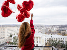 Redhead Woman Holding Red Balloons In Balcony
