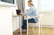 © Atlas - A woman with a cup of coffee is working on a laptop