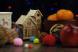 Wooden decorative houses surrounded by a mug of tea, fruit and a knitted scarf symbolize home comfort and warmth. Houses, night and lights in an interior poster.