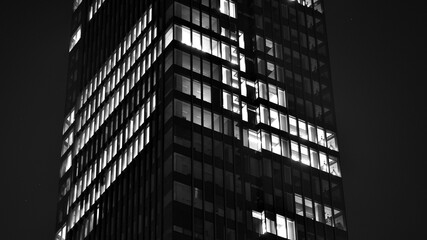 Wall Mural - Pattern of office buildings windows illuminated at night. Glass architecture ,corporate building at night - business concept. Black and white.