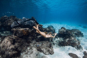 Wall Mural - Sporty woman dive and swims with corals in transparent blue ocean. Freediving with beautiful girl in tropical sea