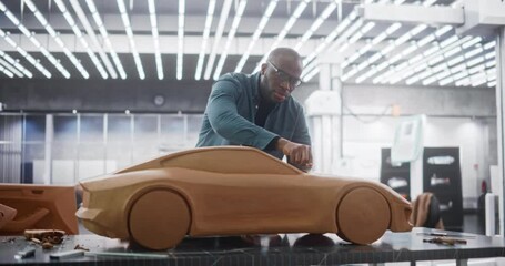 Wall Mural - Black Creative Automotive Designer Working on a Prototype Car Out of Polymer Modeling Clay. Focused Professional African Modeler Contemplating the 3D Sculpture, Looking Thoughtfully at the Model