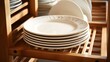Empty white plates stand in a wooden dish rack. Dishes assortment.