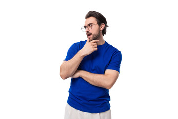 Wall Mural - young suspicious brunette european man with a well-groomed beard in a blue t-shirt on a white background with copy space