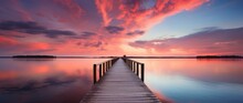  A Wooden Pier Over A Calm Lake During Sunrise