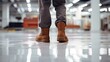 Close-up of a worker wearing boots standing on a new epoxy resin floor in a large, brightly lit room after renovation.