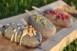 Ice cream popsicle covered in chocolate with walnut, pistachio and raspberry flavor on wooden board in sunlight on grass
