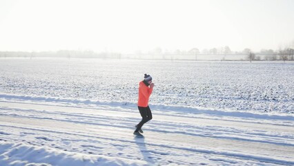 Wall Mural - Male runner jogging on winter snowy road, preparing for competition. Winter running exercises. Athlete training at cold frozen day