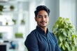 © id512 - happy smiling Indian business man leader looks away with confidence, standing in the office, smiling young professional businessman manager and executive from India