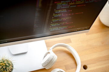 Wall Mural - html code on the screen of a white monitor standing on a wooden table with a keyboard, a coworking o