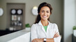 Smiling woman in a clinical setting with dental equipment in the background.