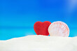 Red heart with conch on sand of beach behind sea. Valentine's Day, wedding, honeymoon, holiday in hot countries. Copy space