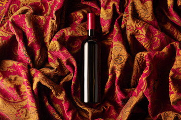 Wall Mural - Bottle of red wine on a retro tapestry with dark red and golden floral ornament.