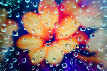 Close-up Of Water Droplets On Glass Over A Blurred Floral Pattern With Vibrant Orange And Purple Hues