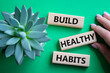 Healthy habits symbol. Concept word Build Healthy habits on wooden blocks. Doctor hand. Beautiful green background with succulent plant. Healthy lifestyle and Healthy habits concept. Copy space