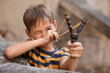 Cute little boy playing with slingshot outdoors