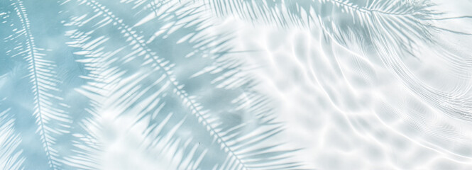 Tropical leaf shadow on water surface. Shadow of palm leaves on white sand beach. Beautiful abstract background concept banner for summer vacation at the beach.