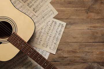 Sticker - Paper sheets with music notes and acoustic guitar on wooden table, top view. Space for text