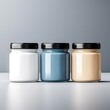Three different colorful cars with black lids isolated on gray background. Studio shot of white, blue and beige glass jars, no labels