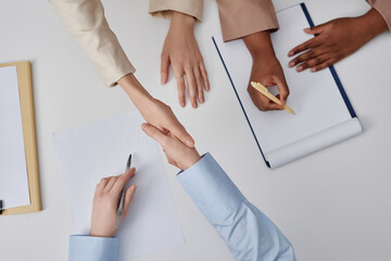 Top down view of unrecognizable business ladies doing handshake after successful meeting at table in company office