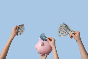 Wall Mural - Female hands with piggy bank, credit card and money on blue background