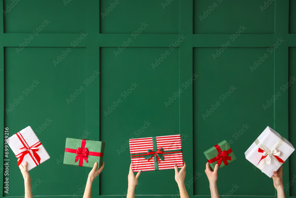 Female hands holding Christmas gift boxes on green background