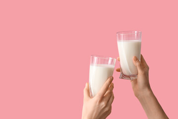 Wall Mural - Hands clinking glasses of milk on pink background