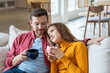 Devoted happy woman holding cup of tea leaning head on shoulder of beloved man. Cheerful man looks at female with loving glance. Love, romance, tenderness, togetherness, closeness in relations