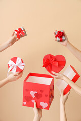 Wall Mural - Female hands with gift boxes on beige background. Valentine's Day celebration