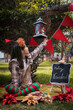 © Claudia - Niña vestida con ropa navideña y gorro de navidad rodeada de decoración navideña en un parque iluminada con la luz del día