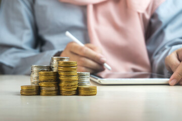 Sticker - muslim businesswoman using a smartphone or tablet with a heap of coins money in the front, symbol for sharia financial banking investment dividend from business growth concept.