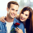 © vgstudio - Love, relationship, dating, sales concept - portrait of happy smiling attractive couple with flower. Man and woman over blurred modern interior or mall background.