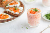Fototapeta Londyn - Appetizer with red caviar, sour cream, dill, onion and rye bread on the white table - the finnish recipe for a holiday food, close up in minimalistic style