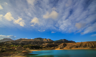 Wall Mural - Lake in the mountains under a blue cloudy sky