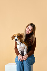 Wall Mural - Portrait of cute Beagle on hands of attractive happy smiling young woman. Friendship between dog and human. Concept of animal, pet lover, friendship, domestic life, companionship. Ad