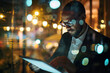 Man in suit using tablet at night with blurred city lights