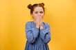 Omg. Portrait of surprised preteen girl child opening mouth and touching face, looking at camera in shock, posing isolated over plain yellow color background wall in studio. People emotion concept