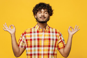 Wall Mural - Young spiritual Indian man he wear shirt casual clothes hold spreading hands in yoga om aum gesture relax meditate try to calm down isolated on plain yellow color background studio. Lifestyle concept