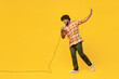Full body young singer Indian man he wear shirt casual clothes sing song in microphone at karaoke club raise up hand isolated on plain yellow color wall background studio portrait. Lifestyle concept.