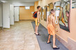 Preteen boys in shorts look in distorting mirrors on wall of locker room side view. Schoolchildren have fun with deformed reflections