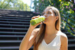 © zigres - Beautiful healthy young woman drinking green smoothie detox juice outdoors