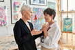 © LIGHTFIELD STUDIOS - side view of happy and stylish lesbian couple of artists talking in modern art workshop, teamwork