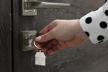 Wall Mural - Woman unlocking door with key, closeup view