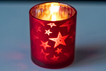 Close-up Scenic View Of Red Glass Candle Holder With Stars Decoration Lying On White Table At Home. Photo Taken December 28th, 2023, Zurich, Switzerland.