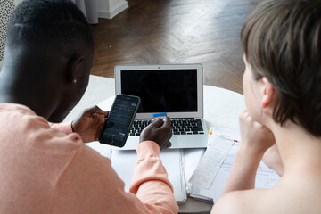 Couple of young people doing house paperwork together on a coach, copy space on laptop screen