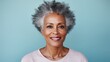 Photograph shows Beautiful gorgeous african-american 50s mid aged mature woman looking at camera isolated on light blue. Mature old lady close up portrait. 