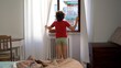 © andrea - Boy Child 9 years old morning  wake  up in the morning in the home bed - he stretches and opens the window to start a new day of school - lifestyle in chilhood after finish of Coronavirus lockdown