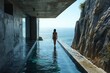 A woman in a swimsuit walks into the crystal clear water of a rocky coastal pool

